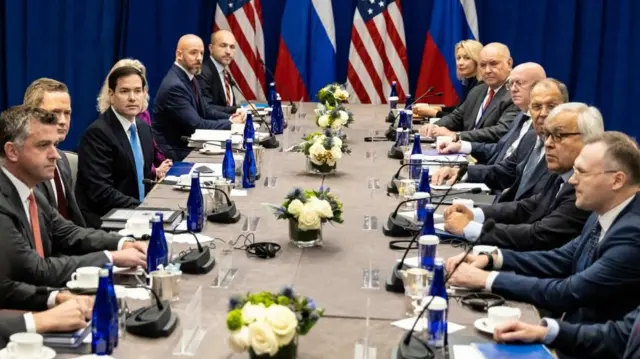 US and Russian delegations facing opposite each other with national flags in background