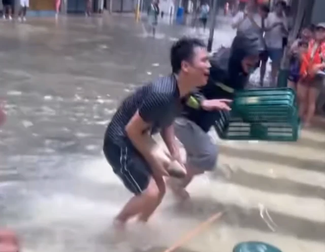 A man catching a fish from the flooded water