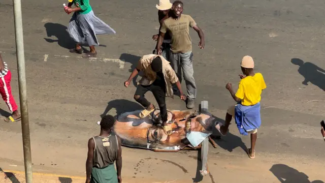 A man jumps on the photo of Lazarus Chakwera's head