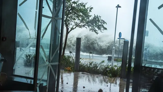 Strong winds and waves seen in the background behind an open glass door