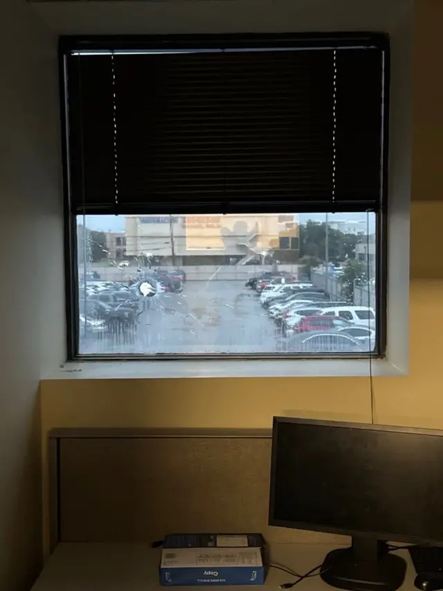 A bullet hole pierce a window in an office