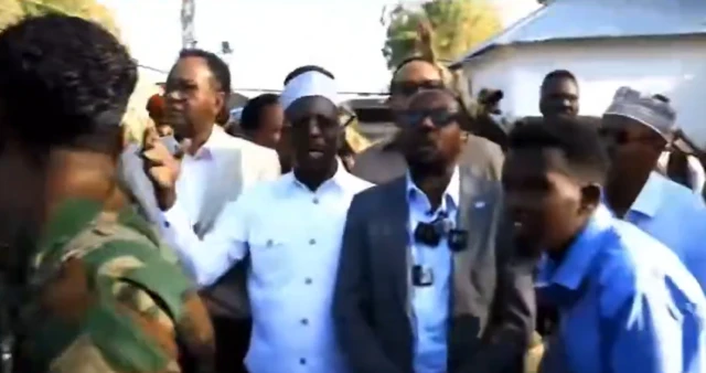 A screenshot of a video with Sharif Sheikh Ahmed and half a dozen other men