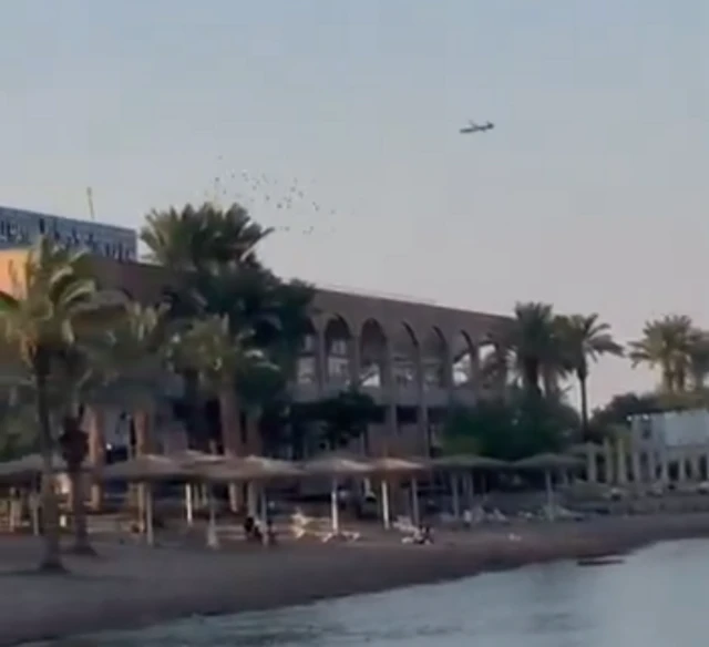 A drone flying low over the top of a large beach-front building
