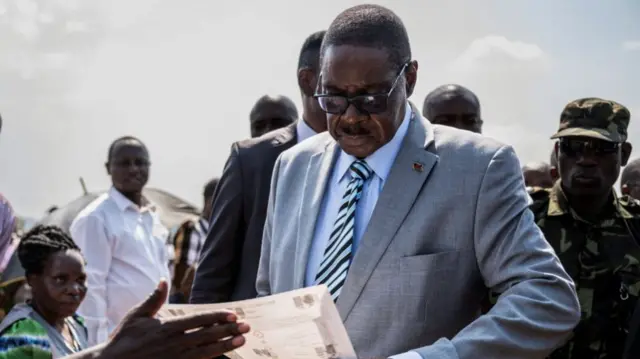 Peter Mutharika, in a suit and glasses, inspects a ballot paper before casting his vote during the general election at Thyolo District, south of Blantyre, Malawi, 16 September  2025