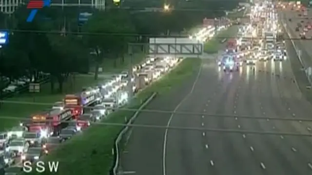 A traffic jam with cars not appearing to move on a freeway with police lights flashing