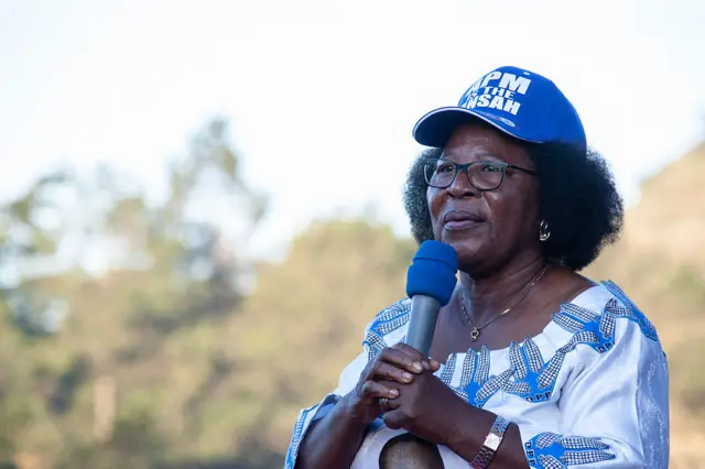 Jane Ansah wearing a blue cap and holding a blue microphone
