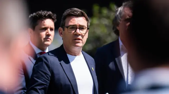 Mayor of Greater Manchester Andy Burnham wearing a white t-shirt and a black suit jacket