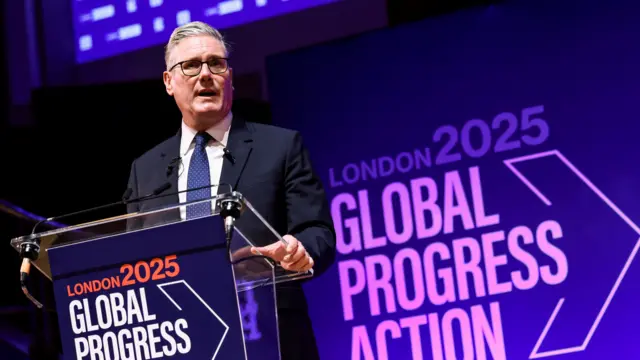 Kier Starmer stands at a podium reading 'London 2025 Global Progress Action'. The image is slightly slanted