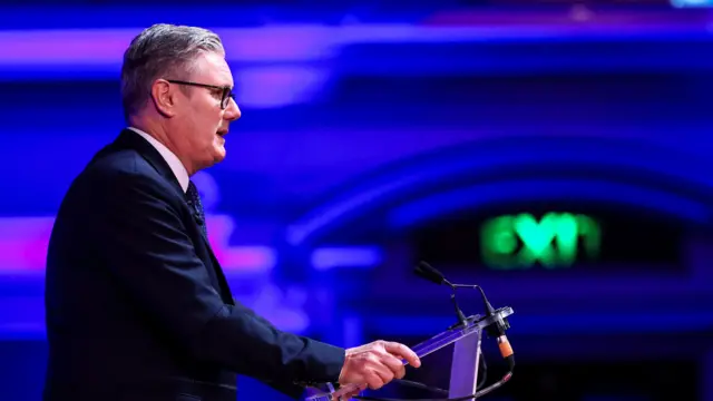 An image of Starmer standing at the podium delivering his speech - taken from the side