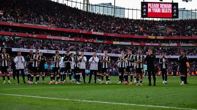 Newcastle players applaud travelling fans at the Emirates stadium