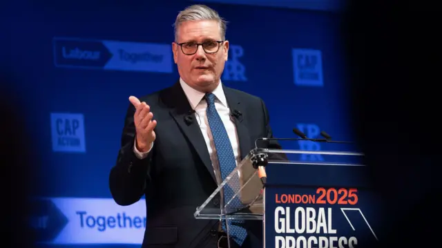 Keir Starmer stands at a podium reading 'London 2025 Global Progress'