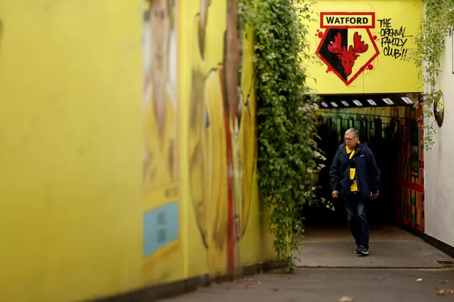 A fan of Watford walks towards the stadium