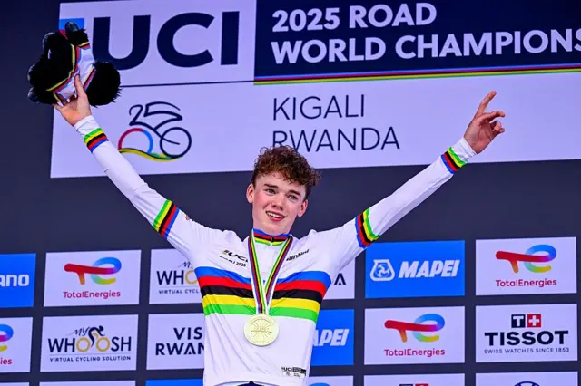 Harry Hudson celebrates on the podium after winning the junior road race