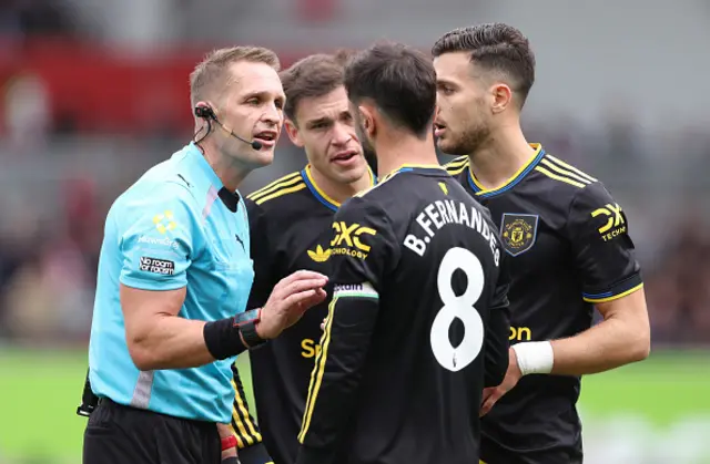 Referee Craig Pawson speaks to Bruno Fernandes of Manchester United