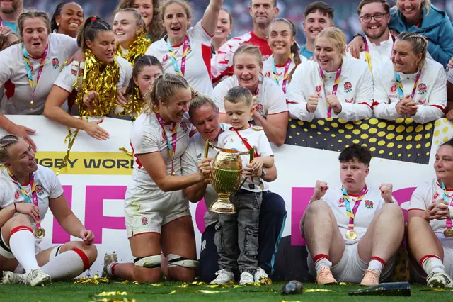 Zoe Aldcroft of England and team mate Marlie Packer lift the trophy with her son Oliver