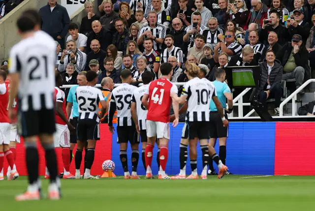Fans of Newcastle United watch as referee Jarred Gillett checks the pitchside monitor