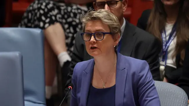 Cooper sitting at UN talking, with mic in front of her