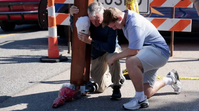 People pray near the church in Grand Blanc, Michigan, where the attack took place
