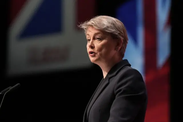 Yvette Cooper pictured at a lectern. She is wearing a black suit jacket.