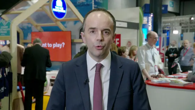 James Murray in a blue suit and a burgundy tie
