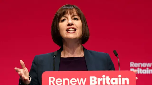 Education Secretary Bridget Phillipson delivers a speech from behind a podium with the sign "Renew Britain" in white over a red background on top. She's in a black blazer and black top
