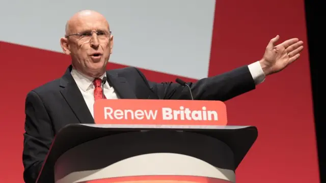 UK Defence Secretary John Healey speaking at podium with a banner that says Renew Britain