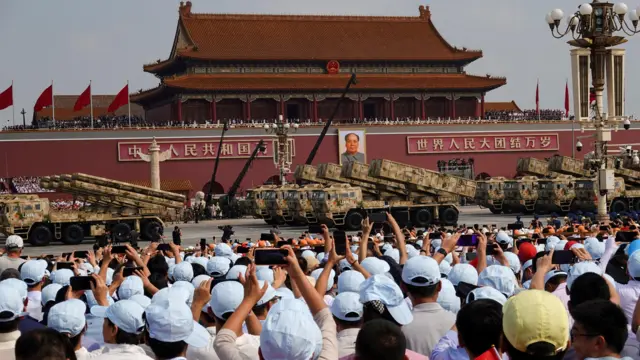 Crowds wearing blue caps gather to watch military parade in Beijing