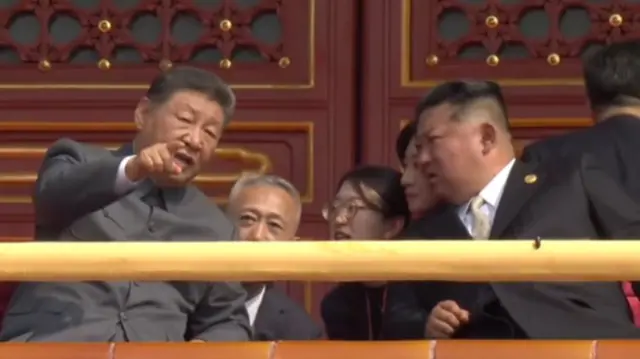 Xi Jinping and Kim Jong Un chat while watching the parade.