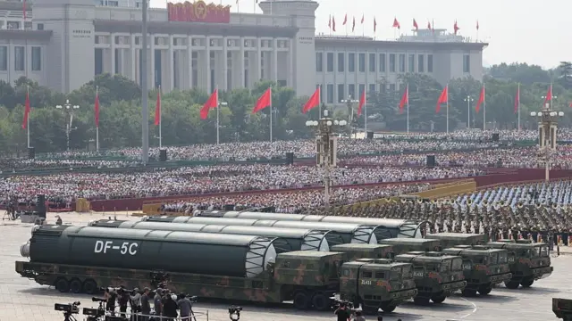 A wide shot of the parade in China. Trucks carry warheads in front of huge crowds
