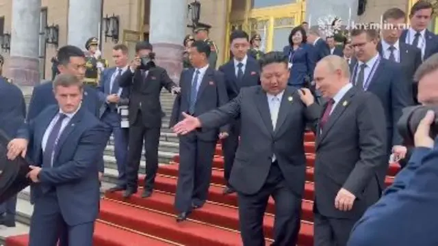 Kim and Putin gesturing as they walk down the stairs