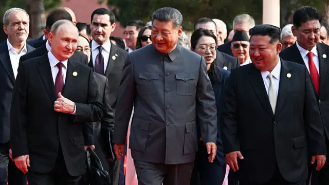 Putin, Xi and Kim smiling as they walk in a row