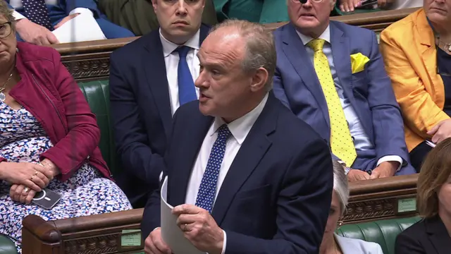 Ed David grips sheets of paper as he asks a question in the Commons