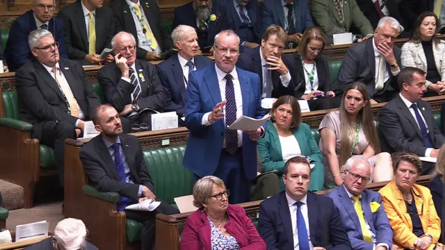 Pete Wishart asks a question, stood among the benches of the Commons