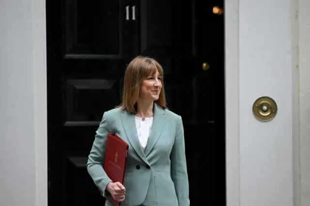 Rachel Reeves in a green suit, behind her is the black door on number 11 Downing Street.
