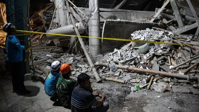Indonesia National Search and Rescue Agency officers take a break after search for survivors at a collapsed building Islamic Boarding School Al Khoziny