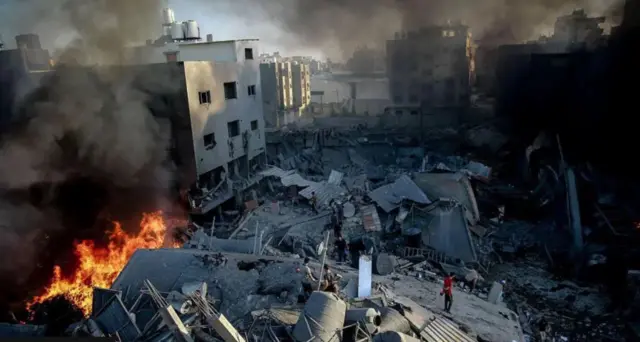 A photo shows destroyed buildings and fires burning in Gaza.