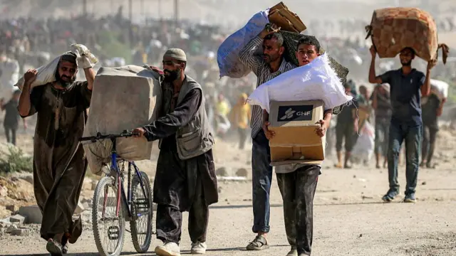 People carrying aid packages they have received from a distribution centre run by the US- and Israeli-backed Gaza Humanitarian Foundation in central Gaza