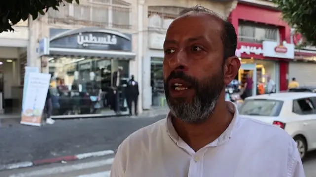 A headshot of Ibrahim Arafat against a shopping street