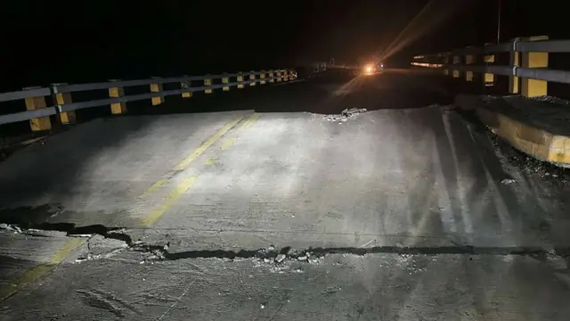 A damaged road is shown at night, with the foremost section pictured cracked and lifted.