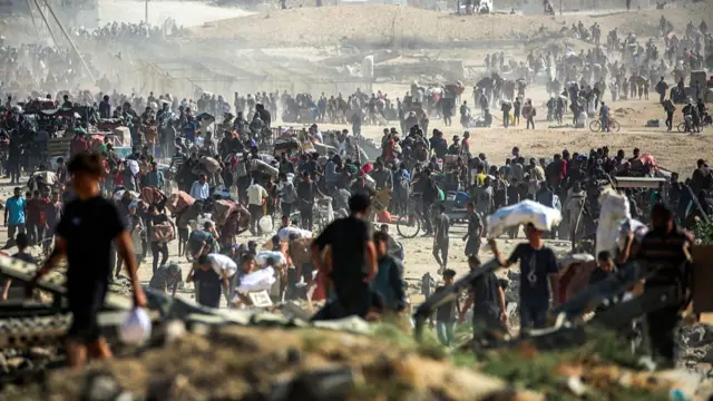 People carrying aid packages they have received from a distribution centre run by the US- and Israeli-backed Gaza Humanitarian Foundation in central Gaza