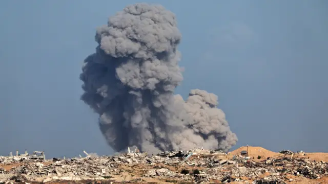 Grey smoke rises from the ground