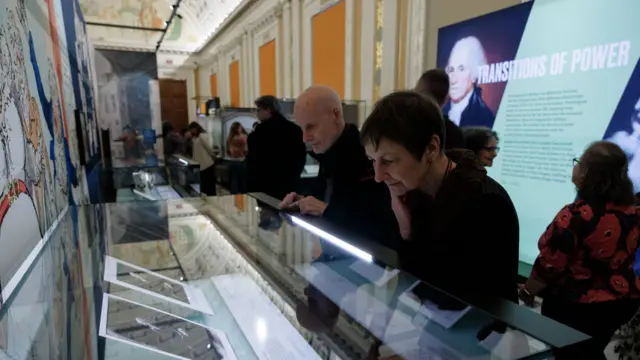 Library of Congress staff preview the "Two Georges: Parallel Lives in an Age of Revolution" exhibition on 24 March 2025. A man and woman wearing black sweaters look thoughtfully at pictures in a disply case.