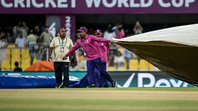 Groundsmen cover the field as it rains during the 2025 ICC Women's Cricket World Cup