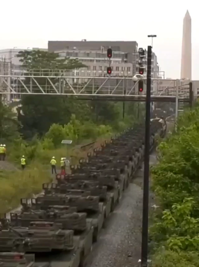 A line of military vehicles moving along what looks like a train track
