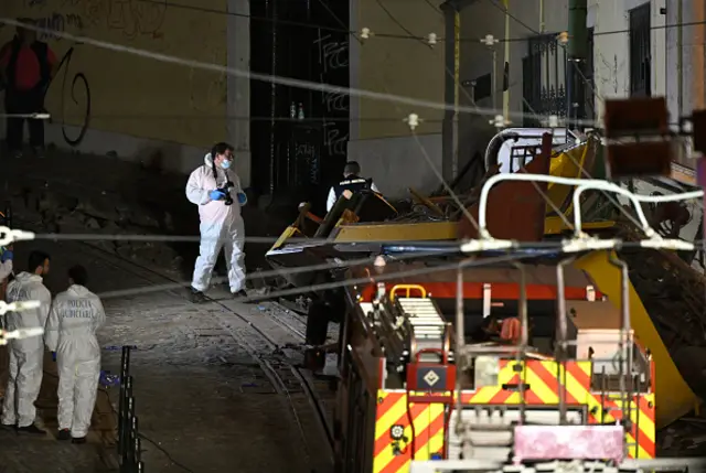 Rescuers and firefighters operate at the scene after the Gloria funicular cable railway derailed in Lisbon. One man in white overalls can be seen holding a camera