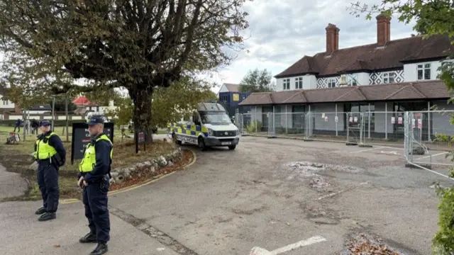Two policemen stand outside the Bell Hotel in Epping