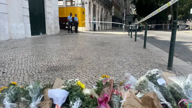 Flowers laid down on a cobbled street behind a police cordon