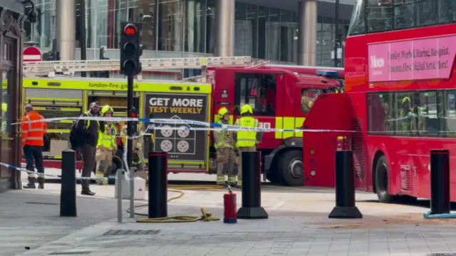 emergency crews stand behind a cordon in the street