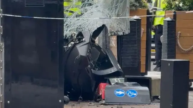 a close-up of the bus's smashed windscreen and debris on the street. people in hi-vis yellow jackets are stood in the background