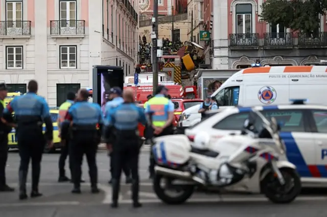 Police and firefighters stand on the site of the Gloria funicular railway accident in Lisbon,